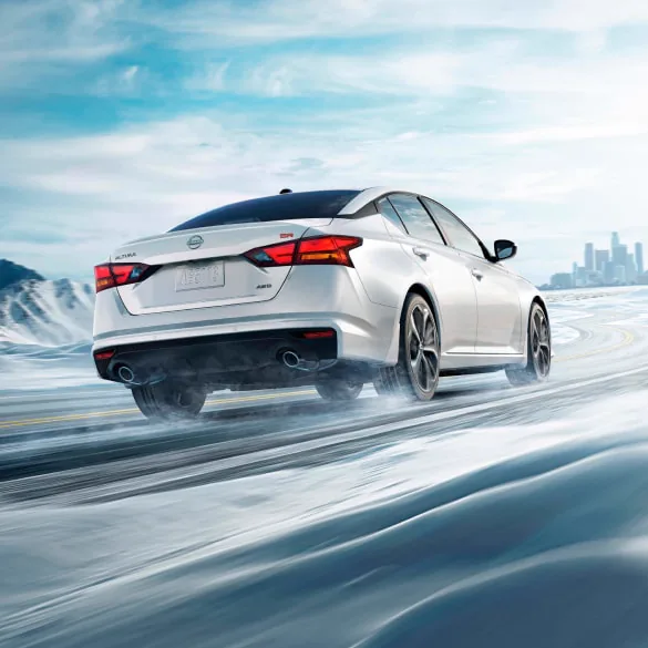 2027 Nissan Altima in white seen from behind driving in snowy landscape illustrating all-wheel drive at Mtn View Nissan of Bristol in Bristol TN